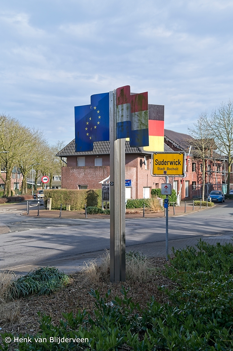 Paal met een stalen vlaggen van Nederland, Duitsland en Euregio op de grens van Nederland en Duitsland